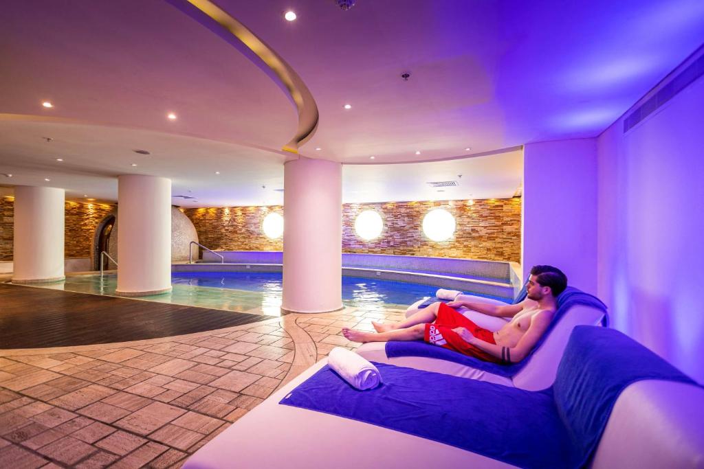 Indoor spa pool with loungers and a guest in the recovery area.