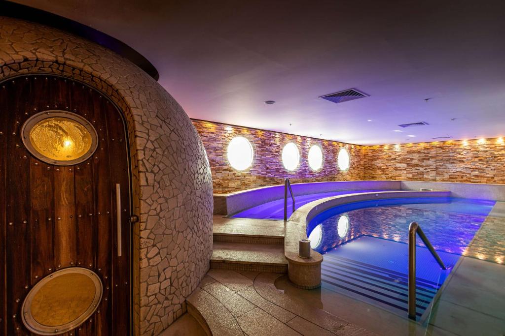 Curved indoor spa pool beside a stone-clad steam room entrance.