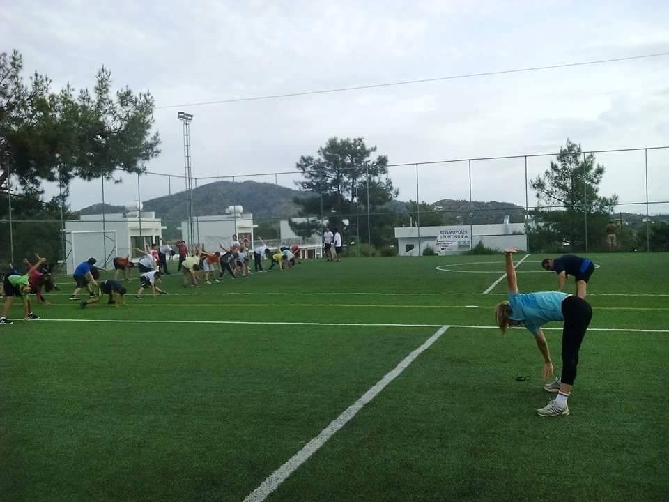 Gruppe von Athleten, die sich auf einem grünen Fußballfeld während einer Aufwärmeinheit dehnen