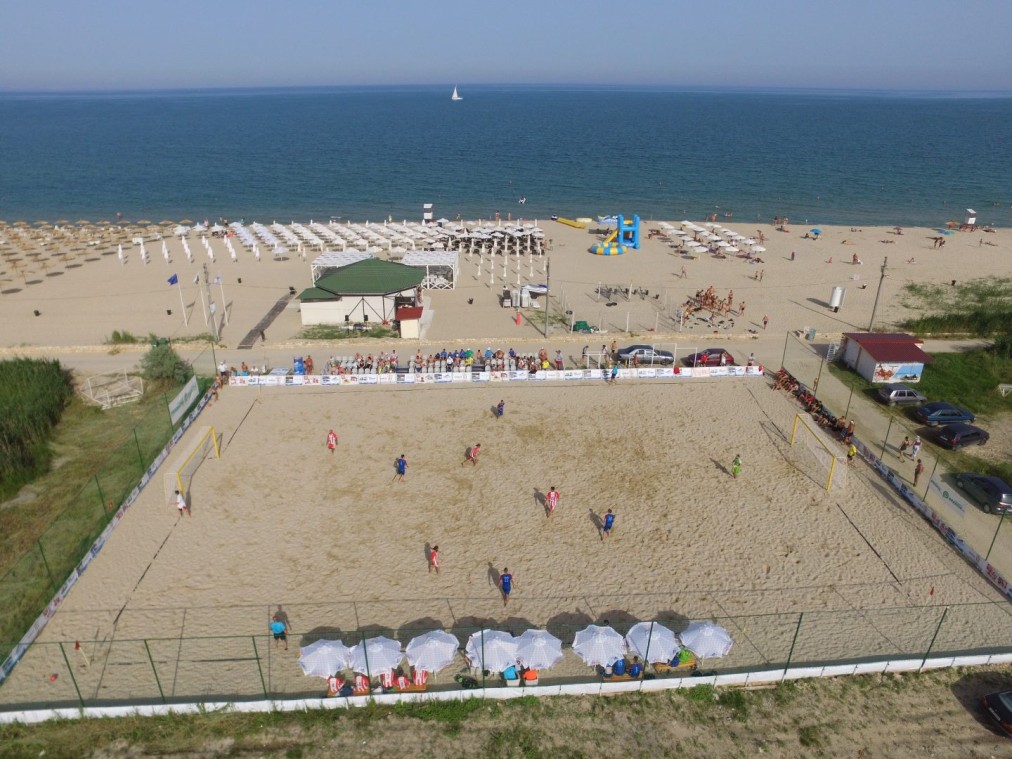 Luftaufnahme von Beachvolleyballplätzen am Meer, auf denen Trainingslager-Übungen und Spiele stattfinden