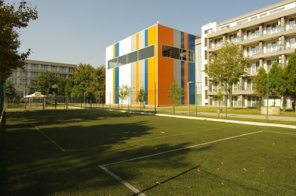 Außenliegendes Kunstrasenfeld neben modernen Gebäuden, markiert für Fußballübungen während eines Trainingslagers