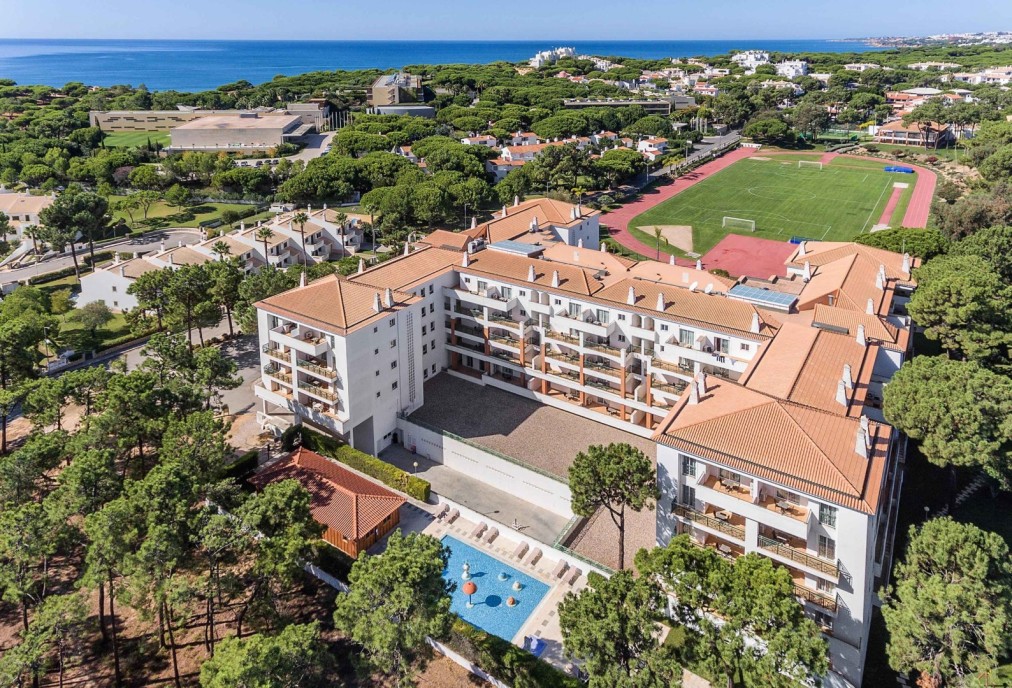 Luftaufnahme des Resorts am Meer mit Laufbahn und Fußballplatz.