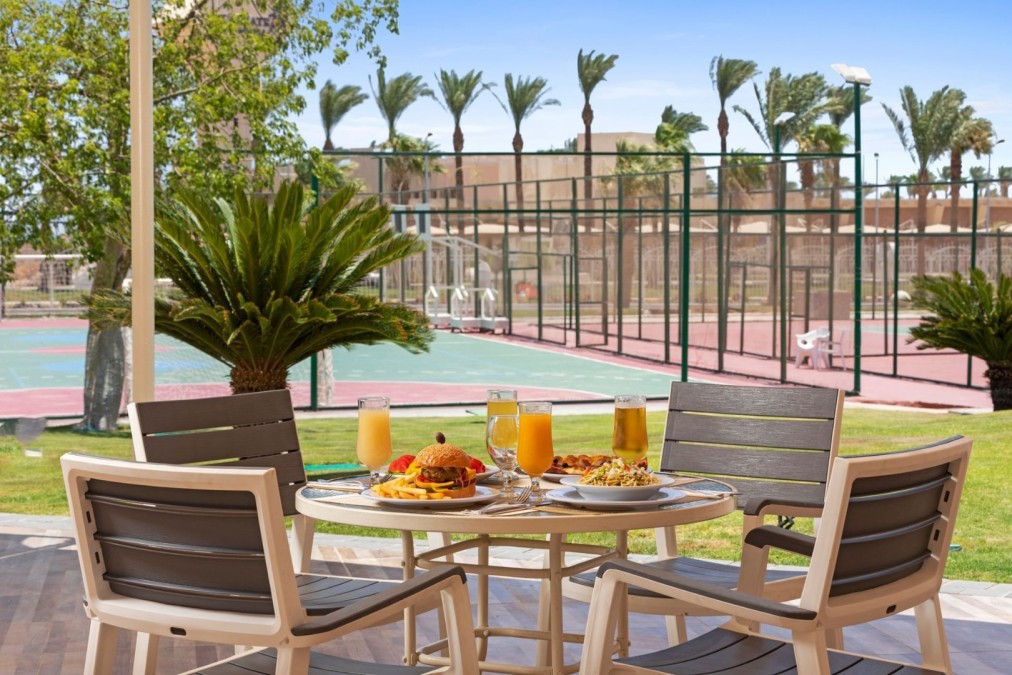 Frühstückstisch mit Saft und Speisen auf einer Terrasse in der Nähe der Tennisplätze