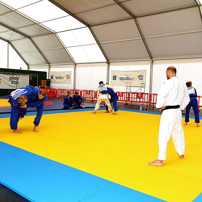 Judo-Training auf Tatami-Matten in einer überdachten Halle.