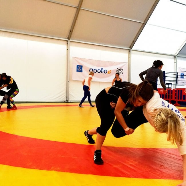 Wrestling-Drills auf einer großen Matte in einer überdachten Trainingshalle.