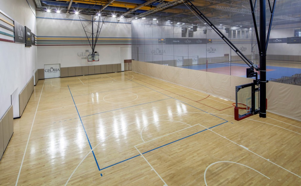 Sporthalle mit vollwertigem Parkettfeld und Basketballkörben, ideal für Training und multifunktionale Nutzung. Trennnetze ermöglichen eine flexible Aufteilung für parallele Einheiten.