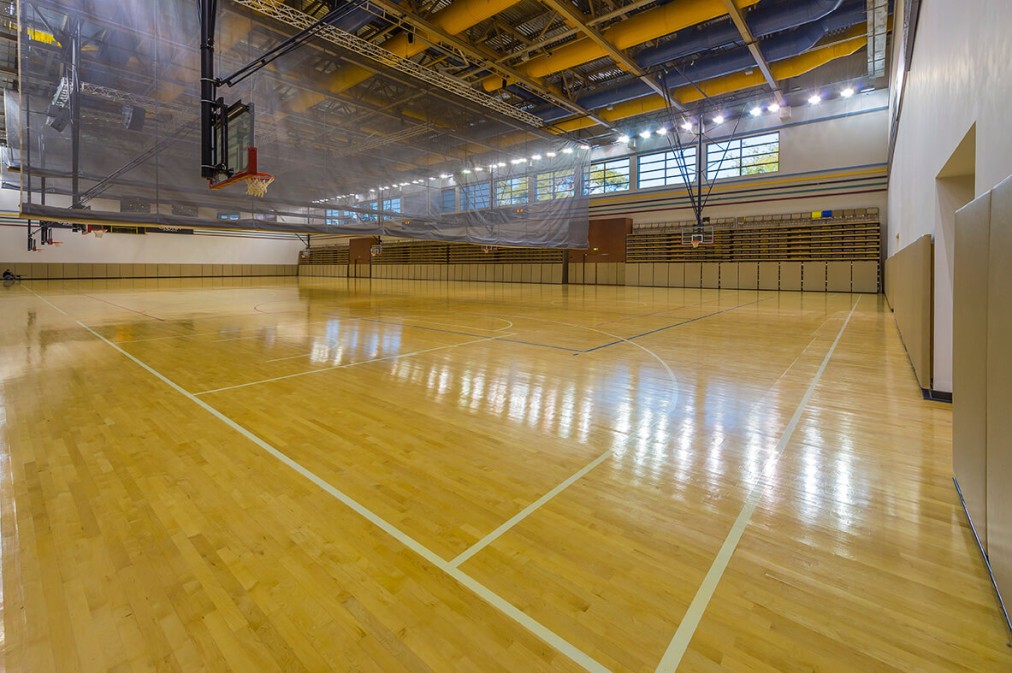 Große Multifunktionshalle mit Basketball-Setup und großzügigen Auslaufzonen für sicheres Spiel. Die Halle lässt sich flexibel für verschiedene Sportarten und Trainingsformate konfigurieren.