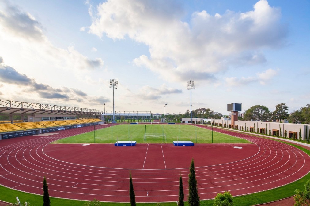 Leichtathletikstadion mit kompletter Laufbahn, zentralem Rasenfeld und Tribünen. Ideal für Bahneinheiten, Athletiktraining und vielseitige Trainingsformate.