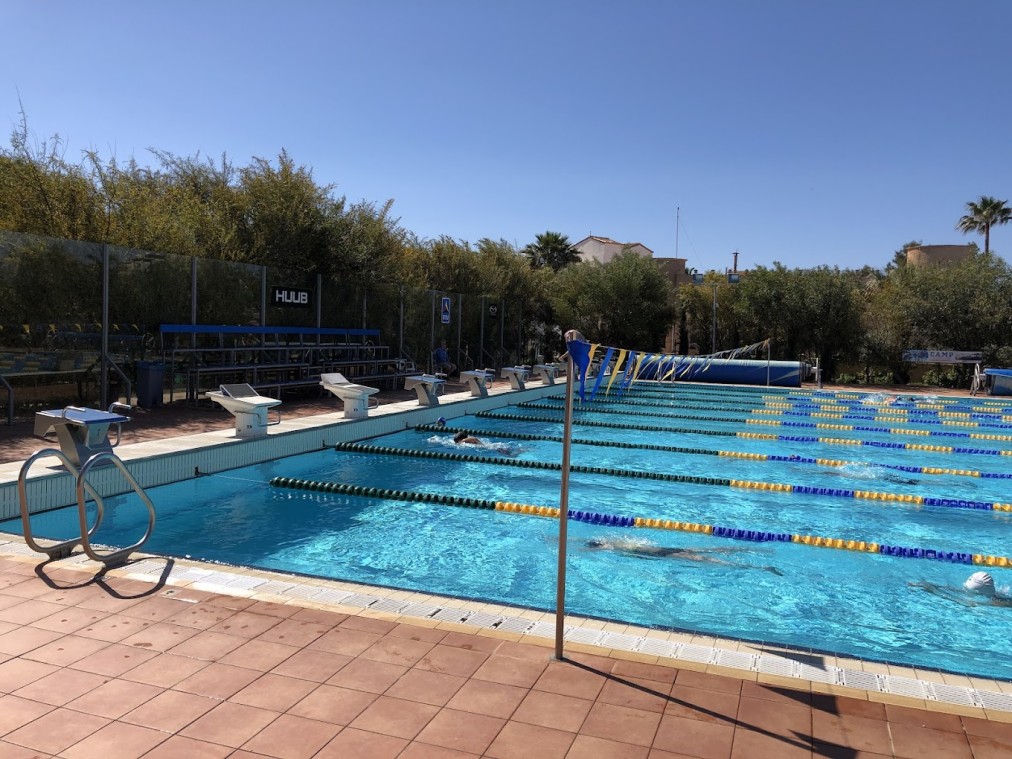 Außen-Trainingsbecken mit Schwimmern, Leinen und kleiner Zuschauertribüne.