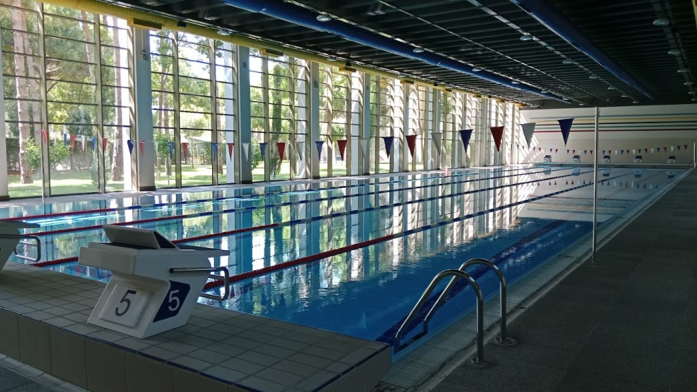 Innenpool mit hohen Fenstern, Schwimmleinen und Startblock am Beckenrand.