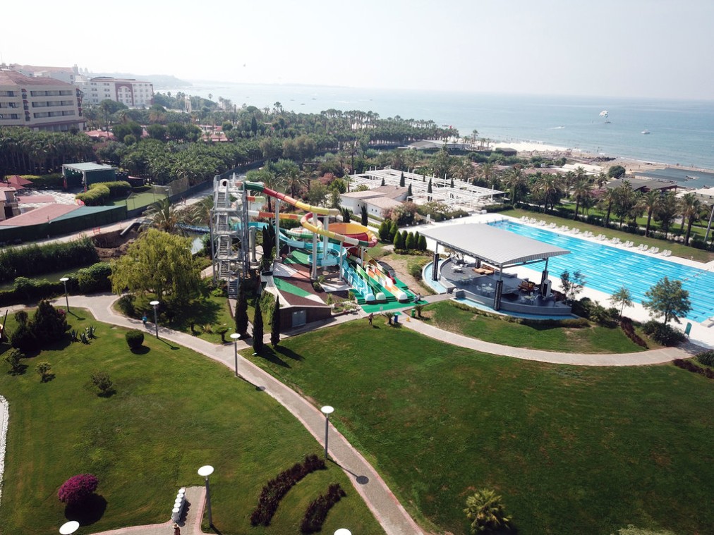 Luftaufnahme des Aquaparks und des olympischen Schwimmbeckens in Gartenanlage nahe dem Strand.