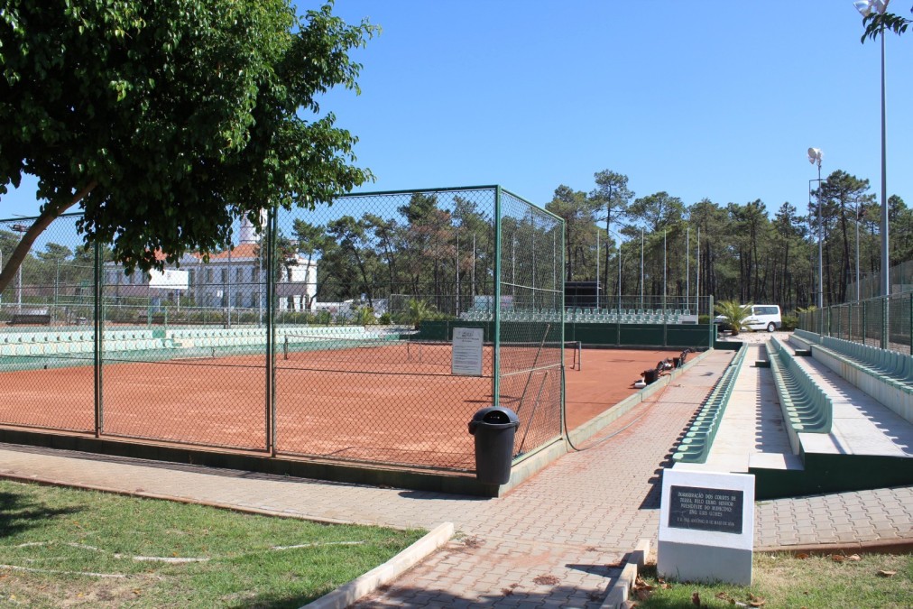 Tennis-Sandplätze mit Zuschauerplätzen und zentralem Weg.