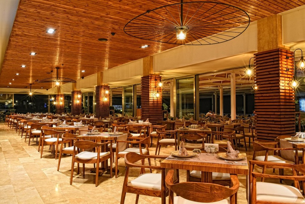 Restaurant mit Holzstühlen, gedeckten Tischen und warmer Beleuchtung unter einer Holzdecke