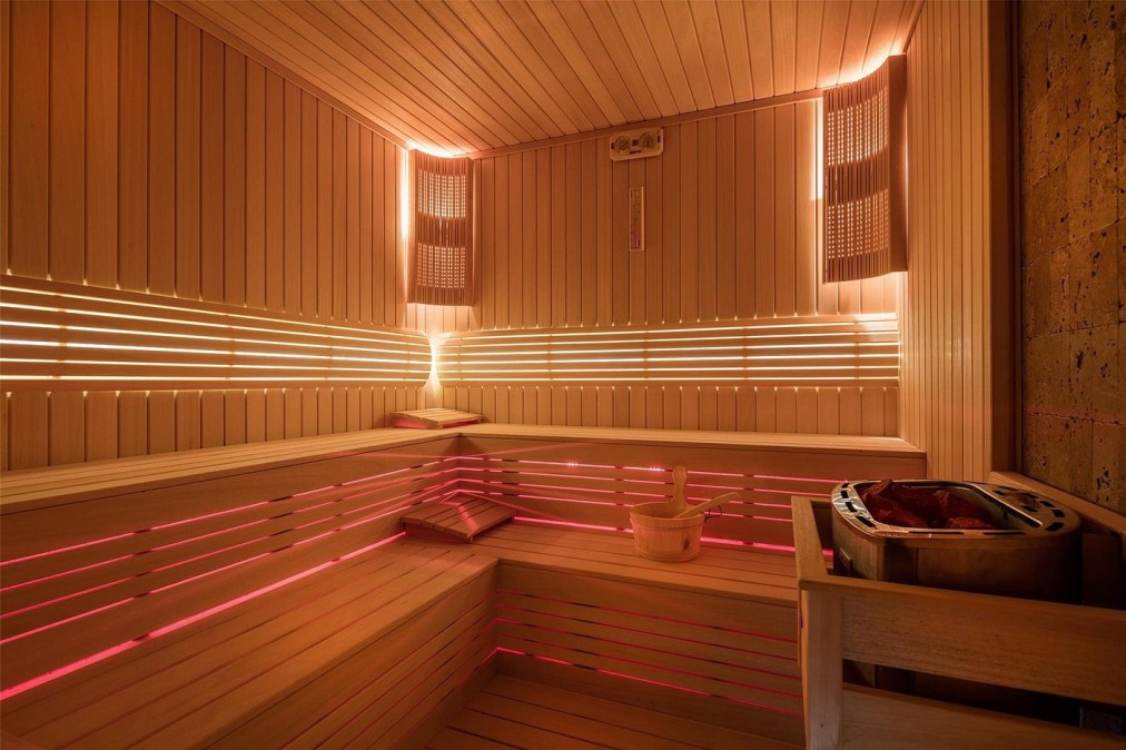 Moderne Sauna mit Holzbänken, LED-Beleuchtung und Saunaofen zur Unterstützung der Regeneration nach dem Training
