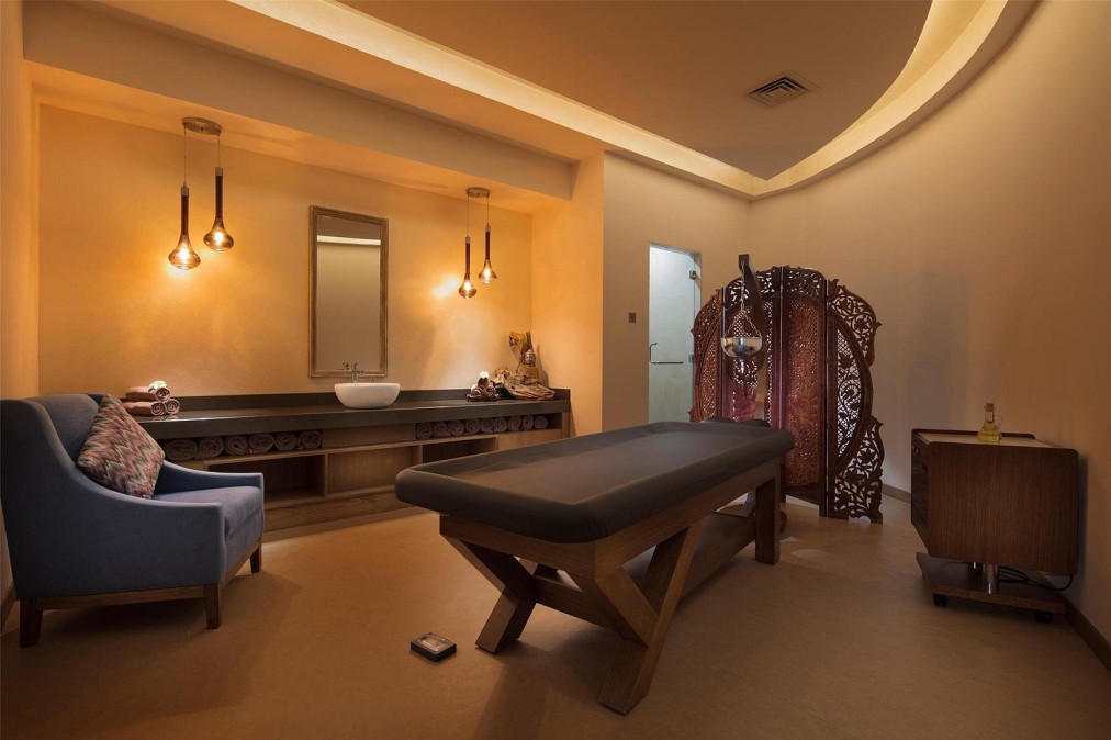 Privater Spa-Behandlungsraum mit Massageliege, Waschbecken und warmer Beleuchtung, genutzt für Therapie und Regeneration von Athleten