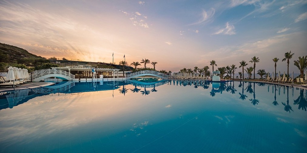 Außenliegender Infinity-Pool mit Brücken, Palmen und Blick auf den Sonnenuntergang