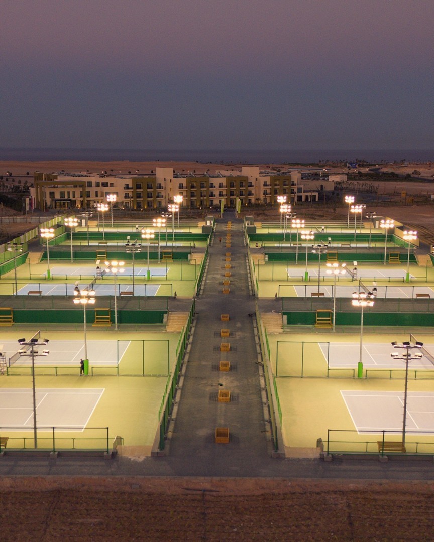 Reihe beleuchteter Tennisplätze im Trainingscamp am Abend