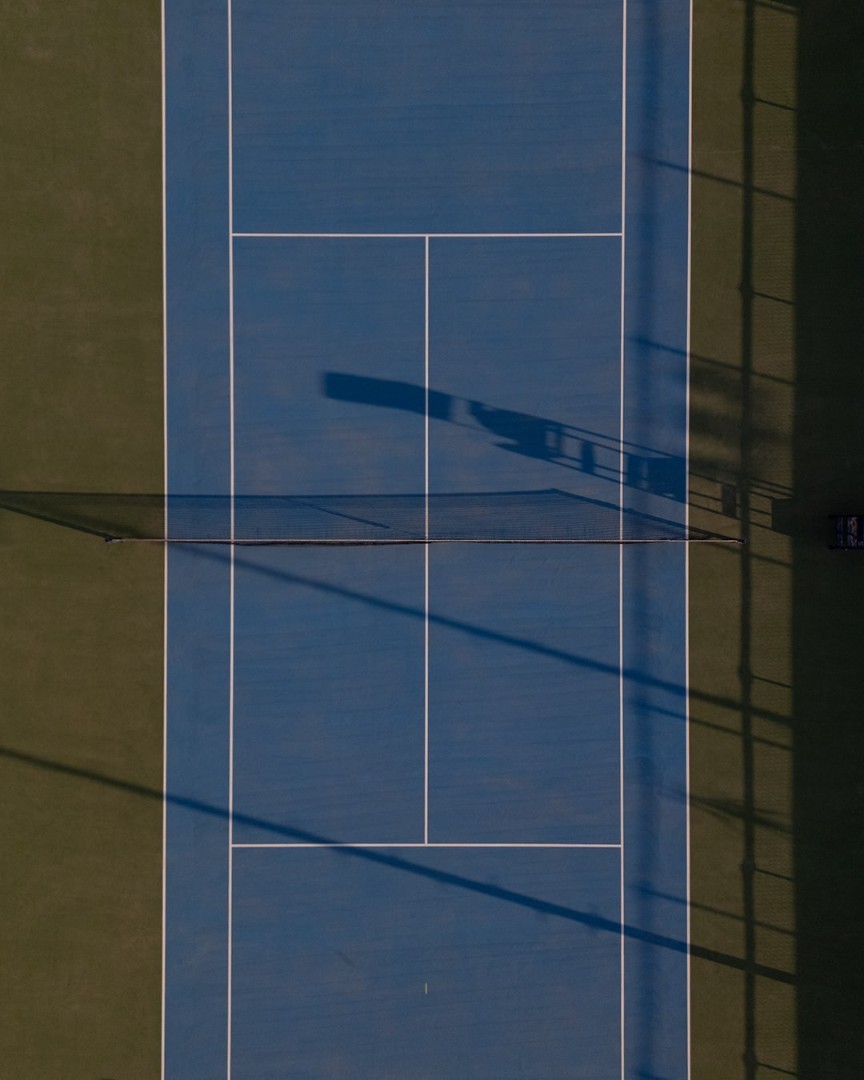 Draufsicht auf einen einzelnen blauen Tennisplatz mit Schattenwurf