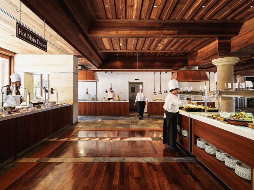 Köche bei der Essenszubereitung im Hotelbuffetrestaurant mit Holzboden und Servicestationen