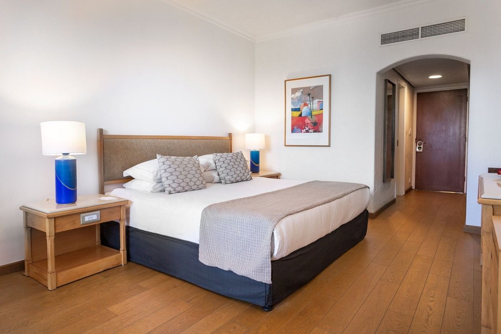 Gemütliches Schlafzimmer mit Kingsize-Bett, Nachttischlampen und minimalistischer Einrichtung für Athleten