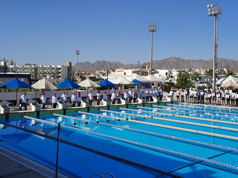 Olympiabecken mit Schwimmern und Trainern während einer Trainingseinheit im Trainingslager unter klarem Himmel