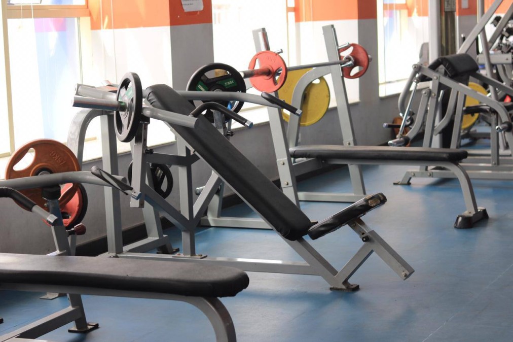 Fitnessstudio mit Hantelbänken, Langhanteln und farbigen Gewichtsscheiben für Krafttraining und Workouts von Athleten