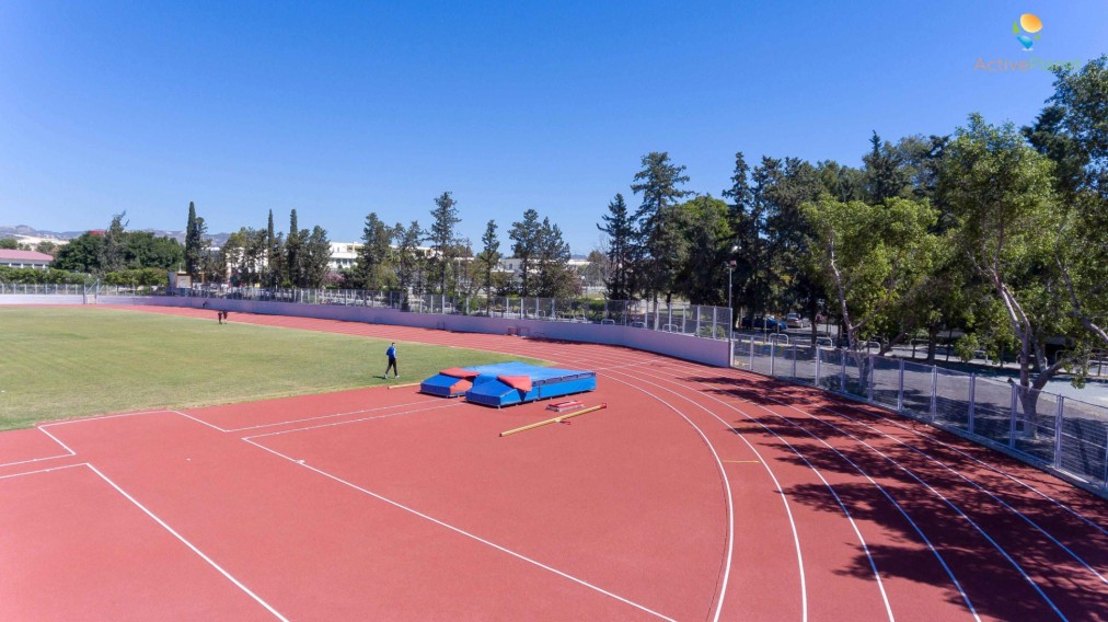 Ecke eines Leichtathletikfelds mit Stabhochsprungmatten und Athleten während des Trainings