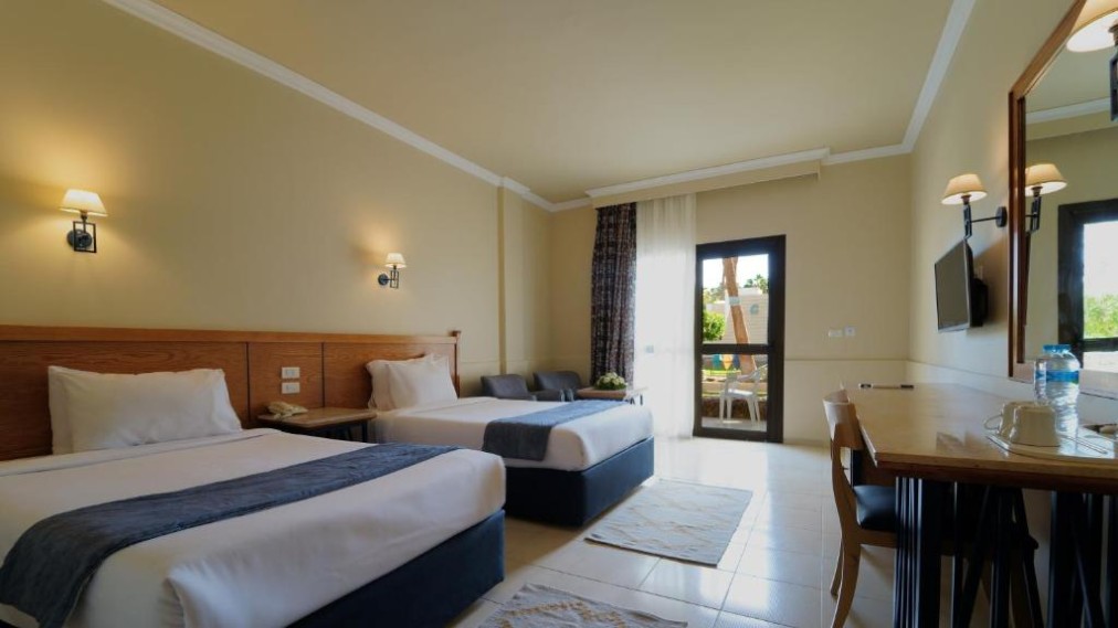 Zweibettzimmer mit zwei Einzelbetten, Schreibtisch, TV und Terrassentür.