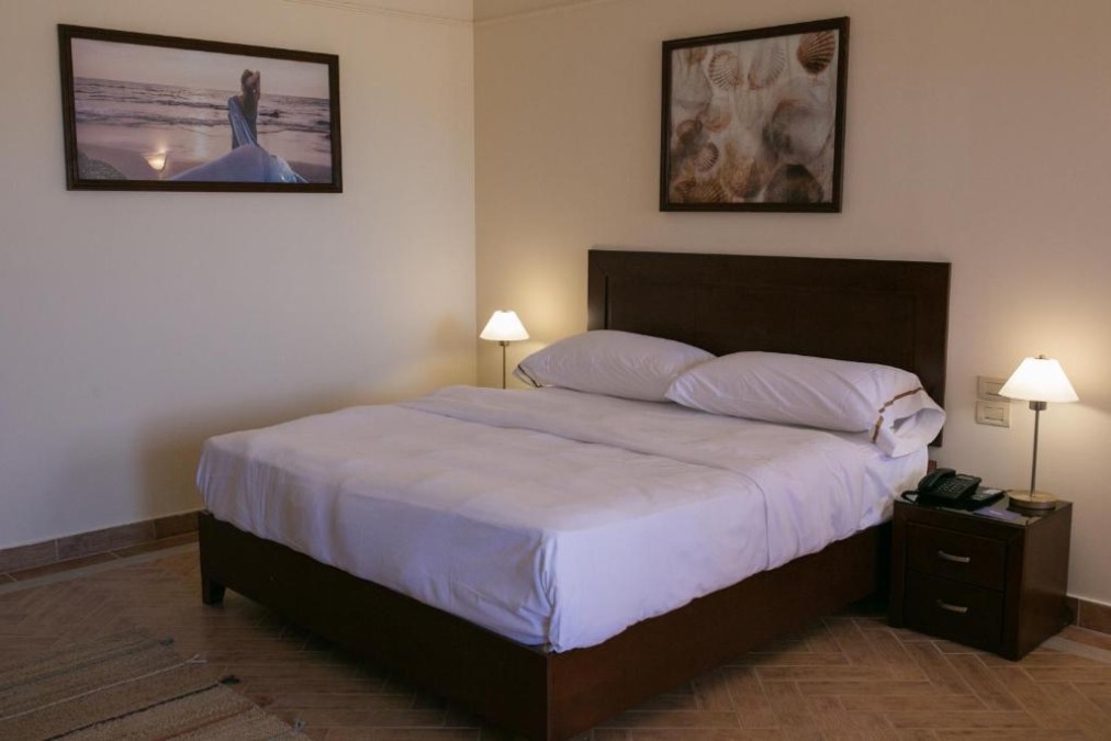 Hotelzimmer mit Doppelbett, Nachttischlampen und Wandbildern für ruhige Aufenthalte.