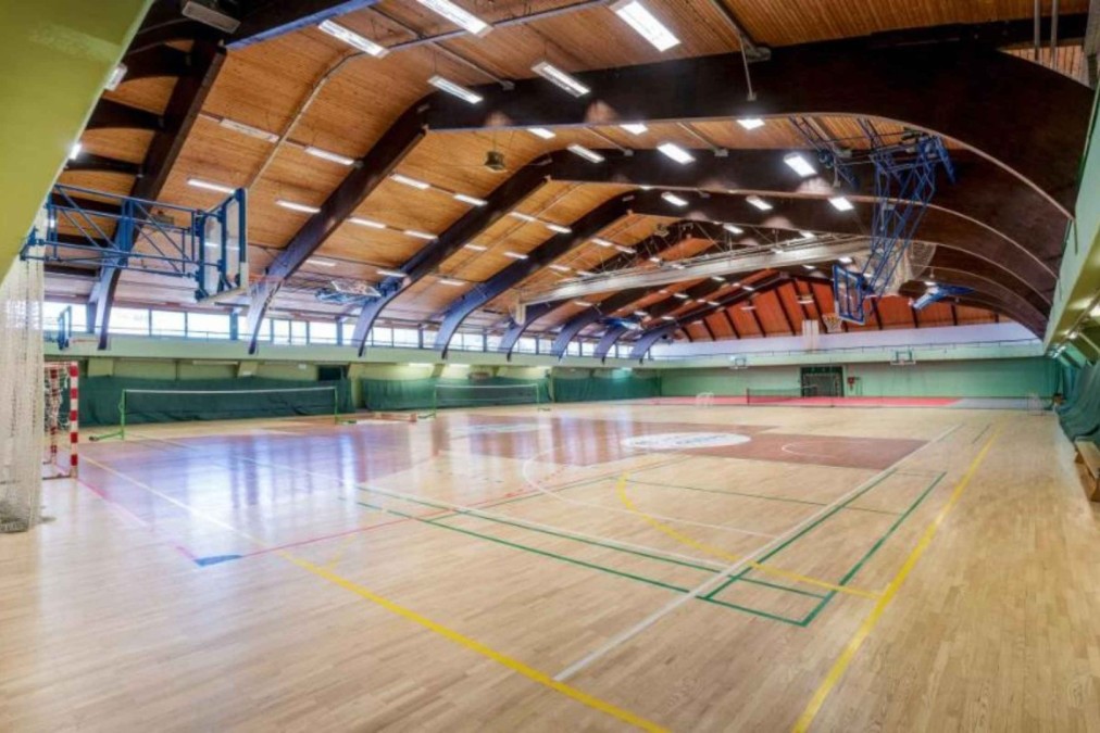 Weitwinkelansicht einer Mehrzweck-Sporthalle mit Basketballkörben und Spielfeldlinien.