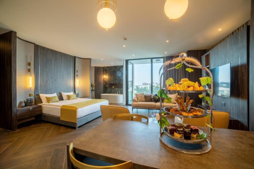 Große Suite mit Doppelbett, Esstisch, Sitzbereich und Badewanne im Zimmer nahe dem Fenster.