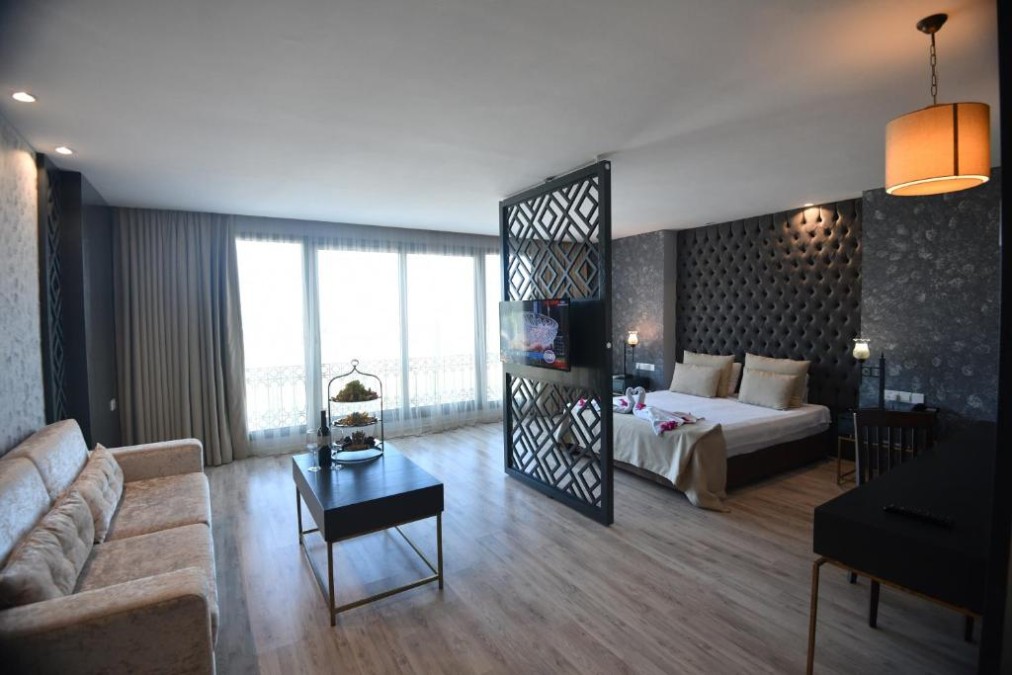 Geräumige Suite mit Doppelbett, Sofa, Couchtisch und dekorativem Raumteiler an Balkonfenstern.