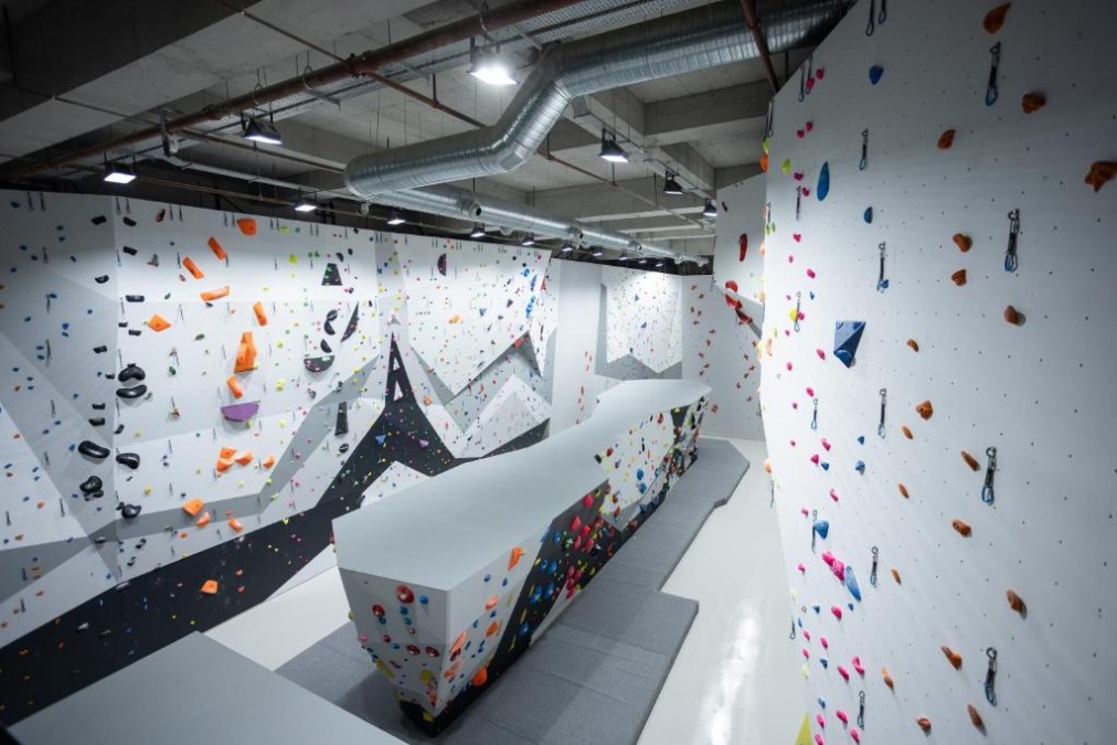 Indoor-Boulderwand mit farbigen Griffen und Sturzmatten für Training-Camp-Einheiten.