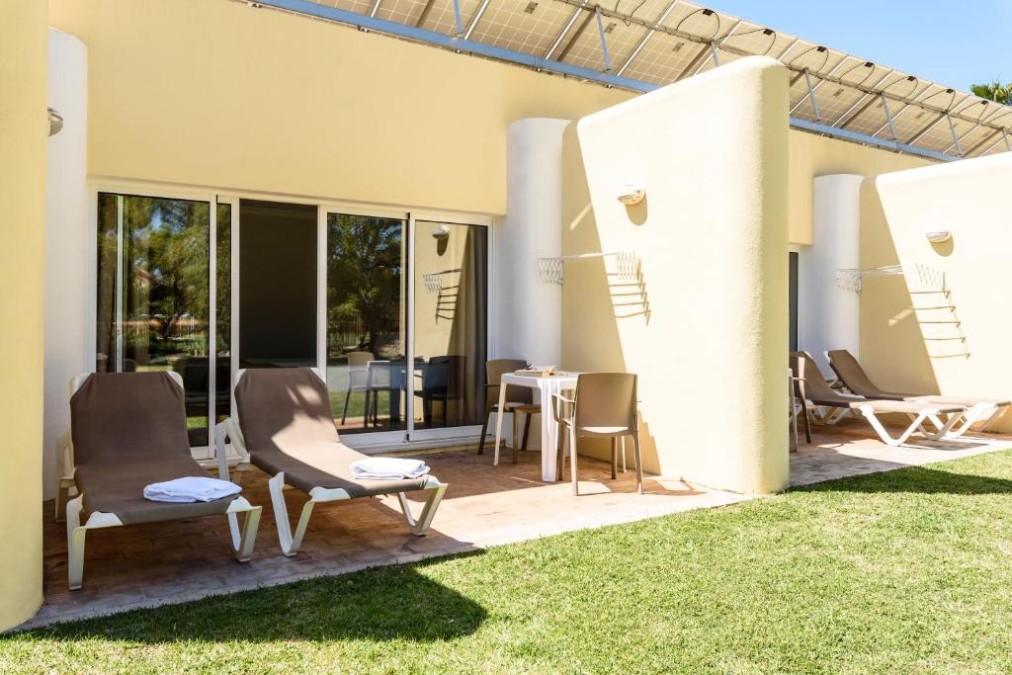 Private Terrasse mit Sonnenliegen und Tisch vor den Gästezimmern.
