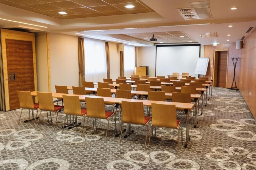 Konferenzraum mit Seminarbestuhlung, Leinwand und Flipchart.
