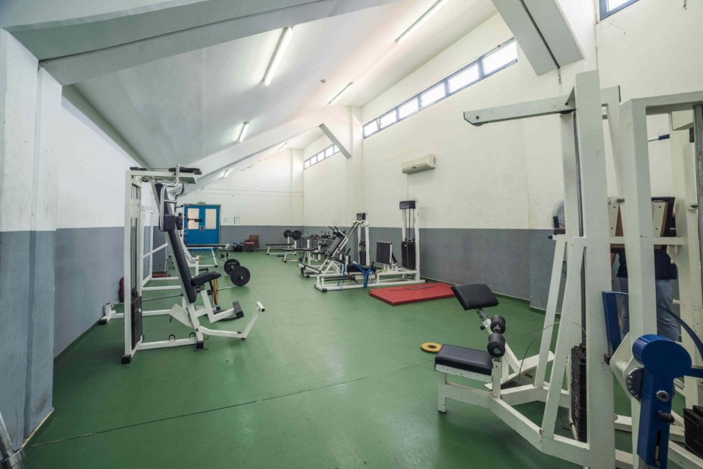 Fitnessraum mit Kraftgeräten, Bänken und Gewichten.
