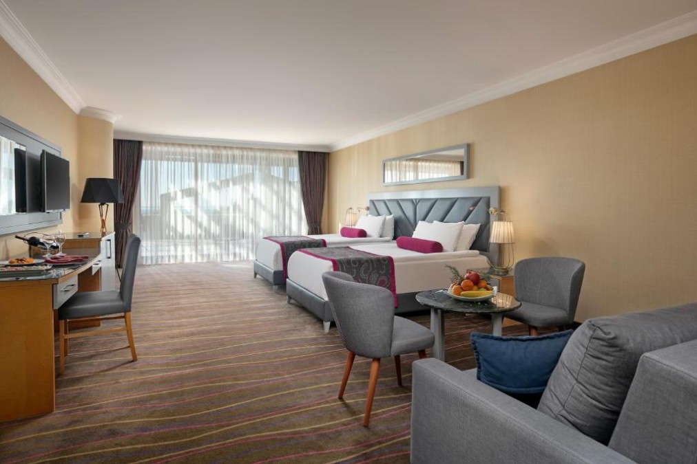 Großes Gästezimmer mit zwei Betten, Sofa, Schreibtisch und Sitzecke.