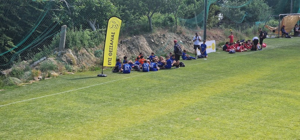 Jugendspieler und Trainer sitzen an der Seitenlinie eines Fußballplatzes.