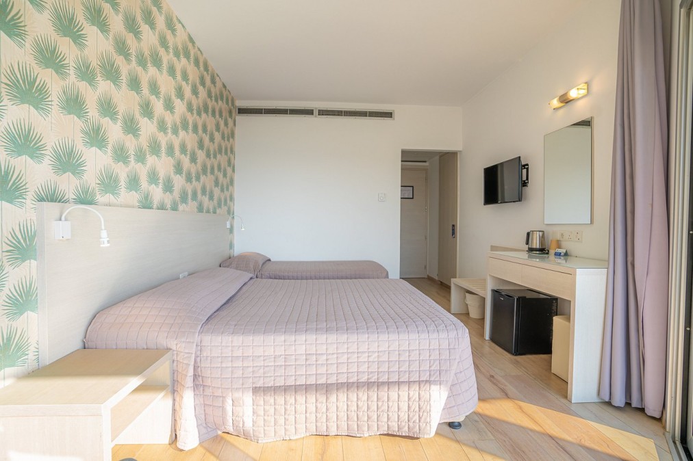 Helles Hotelzimmer mit zwei Einzelbetten, pastellfarbener Tapete und moderner Einrichtung