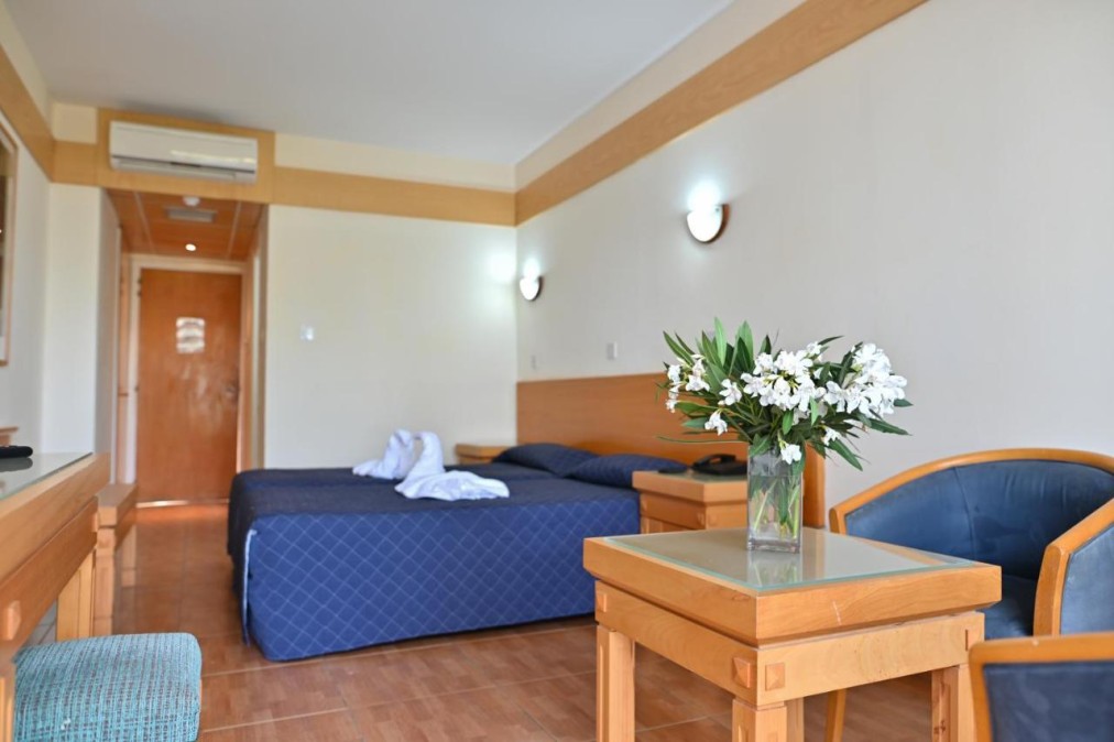 Gästezimmer mit Doppelbett, Sitzecke, Schreibtisch und Blumenarrangement.