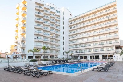 Hotelaußenansicht mit Außenpool und Sonnenliegen im Innenhof.