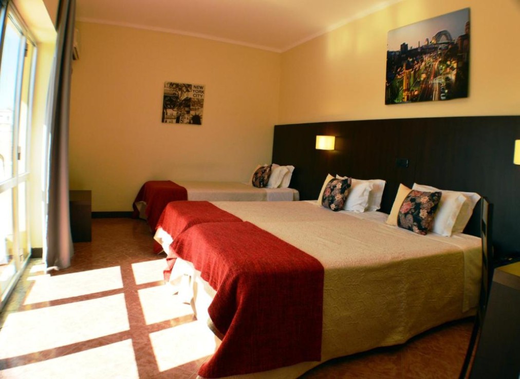 Dreibettzimmer mit drei Einzelbetten und Tageslicht von den Balkontüren.