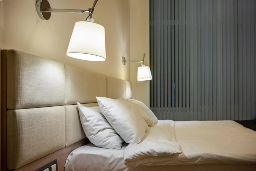Detailansicht eines Hotelbetts mit Leselampen und Kissen, komfortable Unterkunft für Trainingslager-Athleten