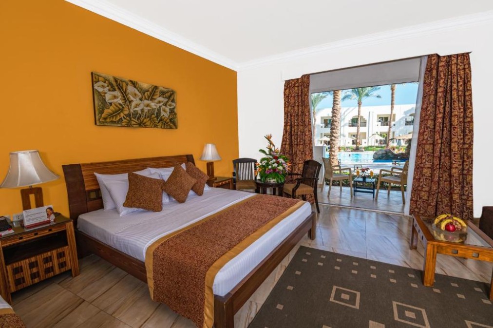 Hotelzimmer mit Kingsize-Bett, warmer Einrichtung und direktem Zugang zur Poolterrasse