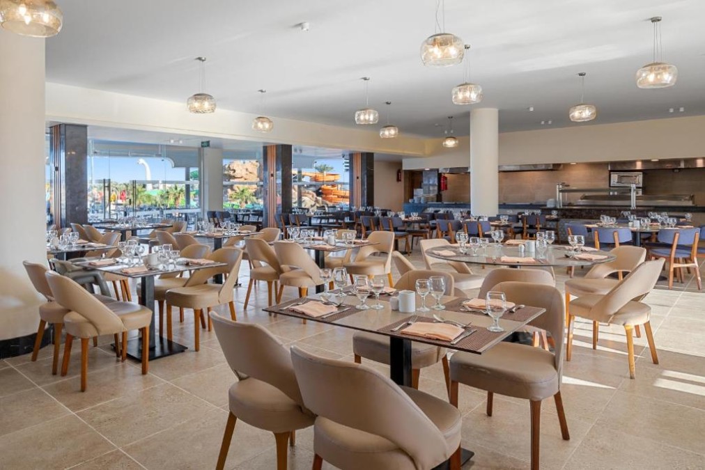 Buffet-Restaurant mit gedeckten Tischen, Gläsern und offenem Küchenbereich.