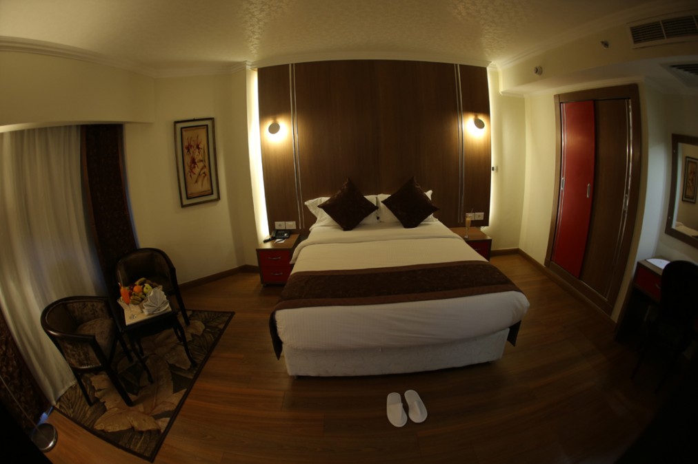Doppelzimmer mit großem Bett, Nachttischen und Hausschuhen auf dem Boden.