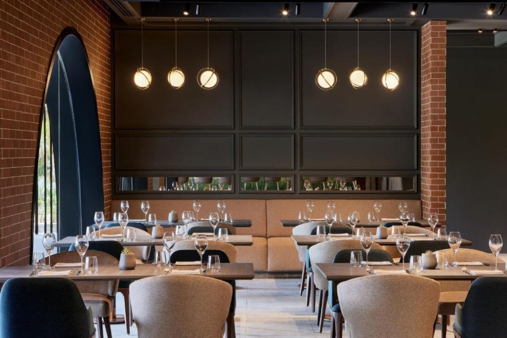 Modernes Restaurant mit gedeckten Tischen, Backsteinwänden und Pendelleuchten.