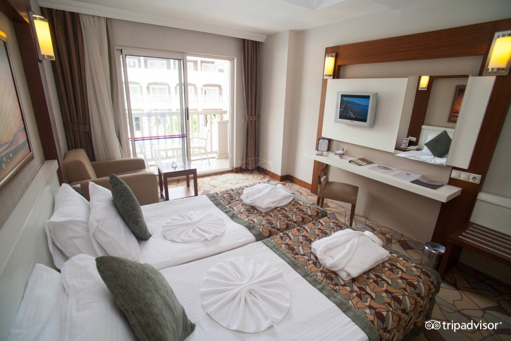 Zweibettzimmer mit Balkon, Schreibtisch, TV und Sitzecke für Trainingslager-Unterkunft.
