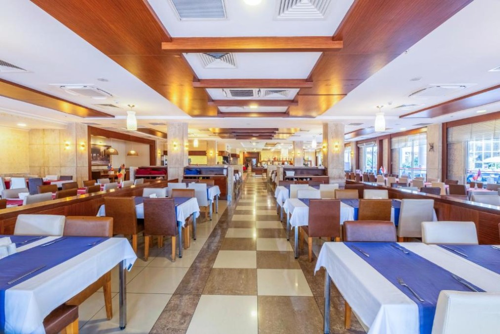 Restaurant-Speisesaal mit gedeckten Tischen, Polsterstühlen und breitem Mittelgang.