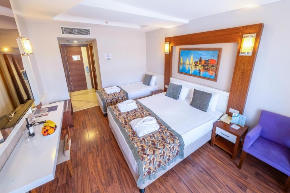 Dreibettzimmer mit Doppelbett und Einzelbett, TV und Schreibtisch.